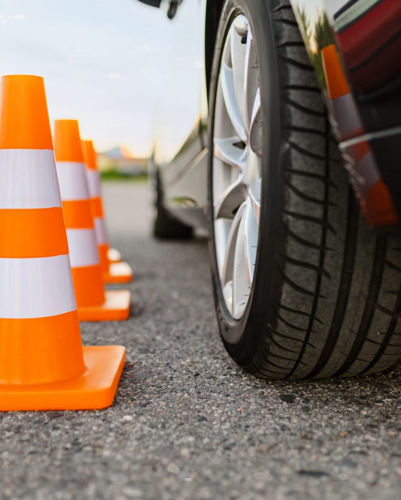 Car and orange traffic cones, lesson in driving school concept, nobody. Teaching to drive vehicle theme. Driver's license education